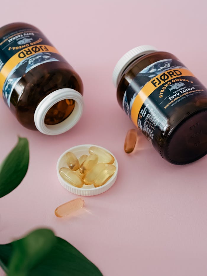 why-choose-us Close-up of omega 3 supplement bottles and capsules on a pink surface.