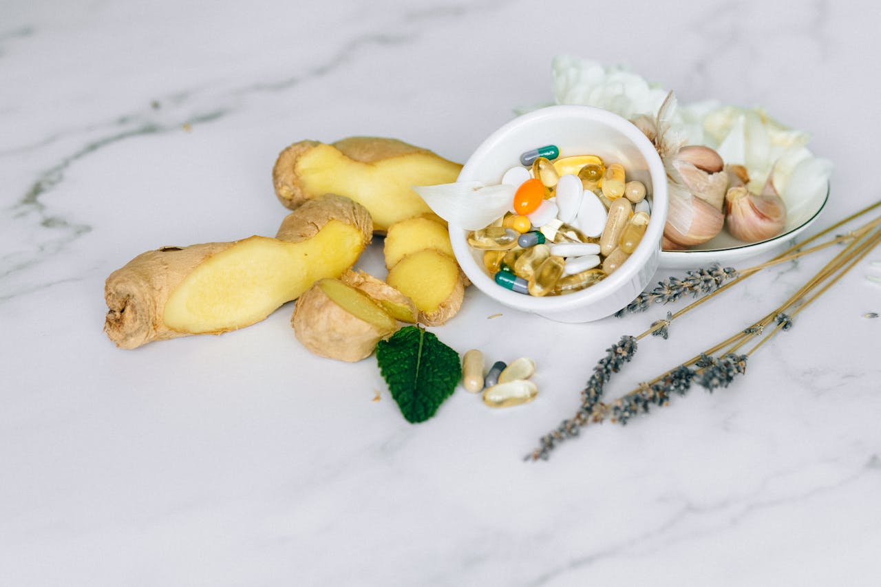 about-01 A flat lay featuring ginger, garlic, and various herbal supplements on a marble surface.